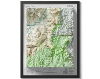 May include: A framed topographic map of a mountainous region with a river winding through it. The map is printed in shades of green, brown, and gray, with elevation lines indicating the terrain. The map is framed in a black frame with a white mat.