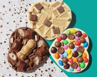 May include: Three heart-shaped chocolate bars with different toppings. The first bar is white chocolate with milk chocolate pieces and the text "Cadbury" printed on it. The second bar is dark chocolate with milk chocolate pieces and a chocolate hippo. The third bar is white chocolate with colorful candy sprinkles.