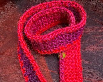 Pink and purple crocheted scarf for dolls and teddybears, vibrant coloures, with one green spot. Measurements 57cm x 3cm.