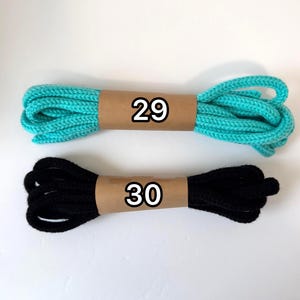May include: Two bundles of rope. One is turquoise, the other is black. Each is wrapped with brown paper, with the numbers 29 and 30 printed on them in black.