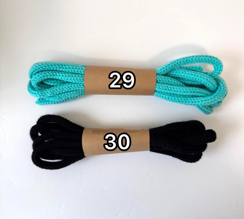 May include: Two bundles of rope. One is turquoise, the other is black. Each is wrapped with brown paper, with the numbers 29 and 30 printed on them in black.