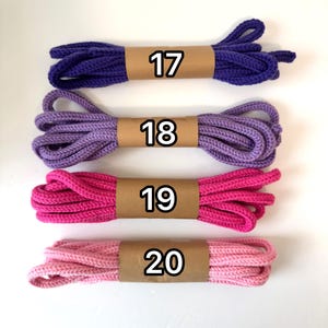 May include: Four sets of braided shoelaces arranged horizontally. The top lace is dark purple labeled 17, followed by a lavender lace labeled 18, a hot pink lace labeled 19, and a light pink lace labeled 20. Each lace is secured with a tan paper band.