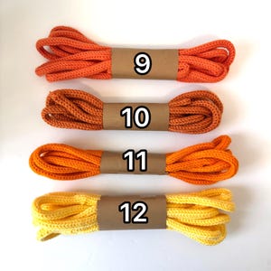 May include: Four bundles of colorful rope in shades of orange and yellow. Each bundle is wrapped with a brown paper band and labeled with a number from 9 to 12. The rope appears to be made of a thick, woven material.