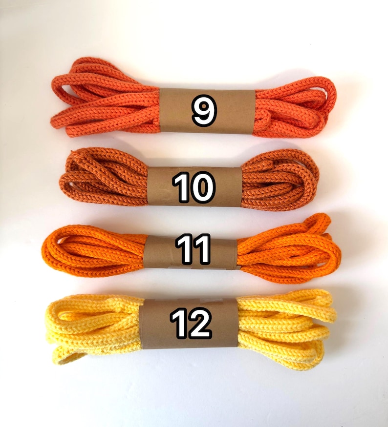 May include: Four bundles of colorful rope in shades of orange and yellow. Each bundle is wrapped with a brown paper band and labeled with a number from 9 to 12. The rope appears to be made of a thick, woven material.
