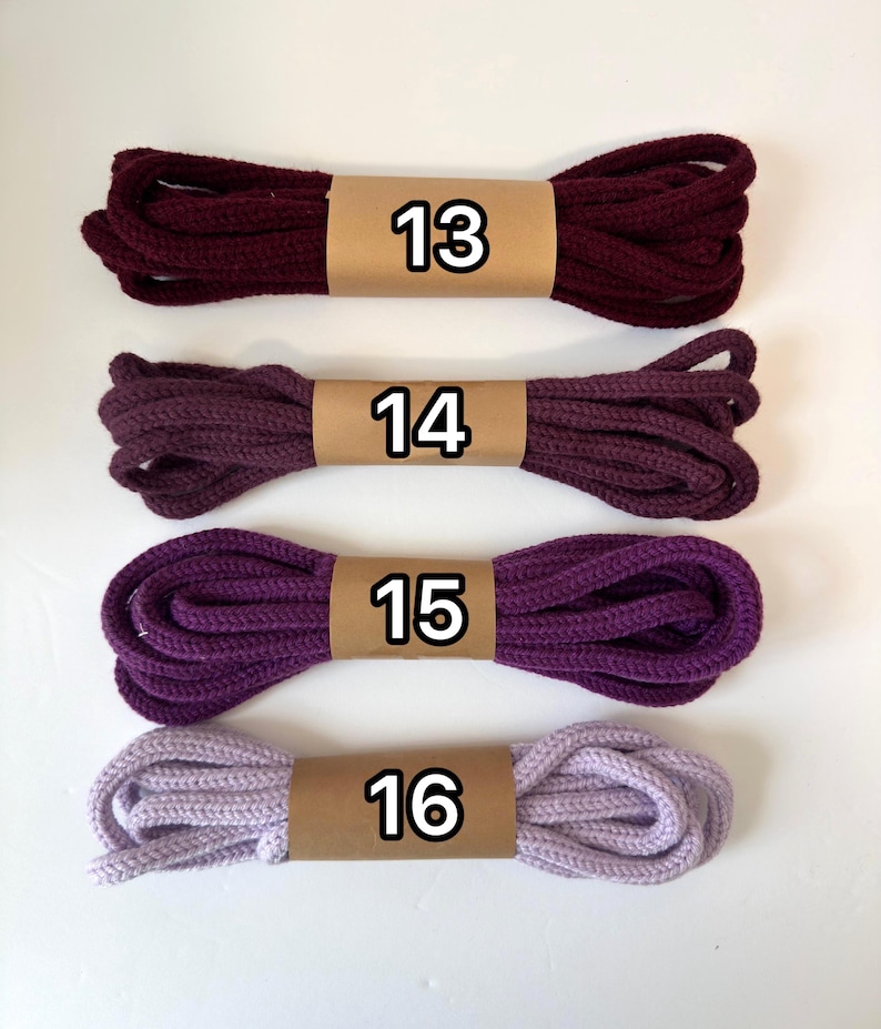 May include: Four bundles of rope in varying shades of purple and burgundy, each wrapped with a brown paper band. The numbers 13, 14, 15, and 16 are printed on the bands. The colors range from deep burgundy to light lavender.