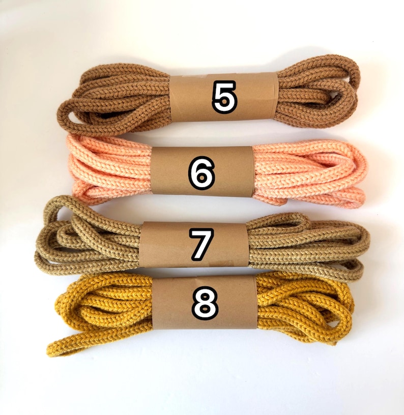 May include: Four bundles of rope in various colors: brown, peach, tan, and mustard yellow. Each bundle is wrapped with a brown paper band and labeled with a number from 5 to 8. The rope appears to be made of a woven material.