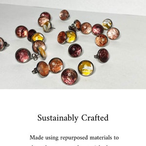 May include: A collection of colorful, round, resin earrings with a metallic finish. The earrings are made from repurposed materials and are designed to be sustainable.