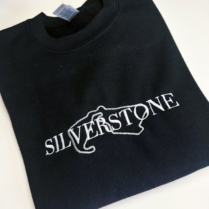 Puede incluir: Sudadera negra con un dise&ntilde;o bordado en blanco del circuito de Silverstone y la palabra "SILVERSTONE" en blanco.