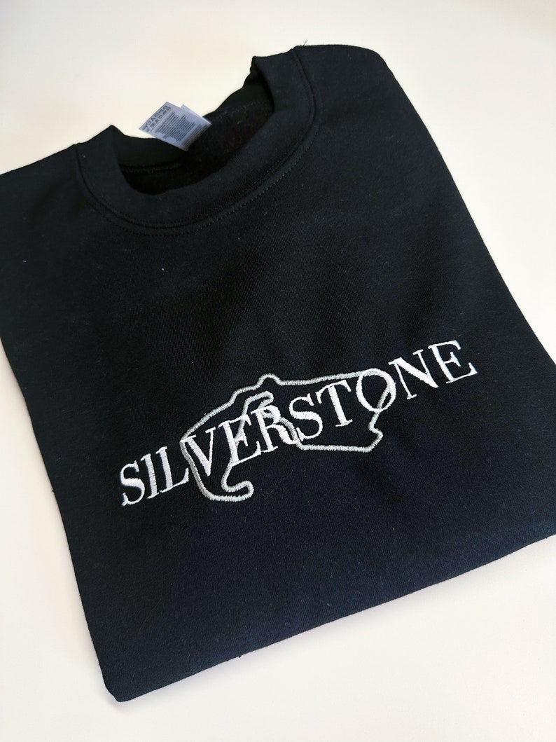 Puede incluir: Sudadera negra con un dise&ntilde;o bordado en blanco del circuito de Silverstone y la palabra "SILVERSTONE" en blanco.