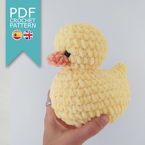 Puede incluir: Un pato de ganchillo amarillo hecho a mano con un pico color melocotón y ojos negros. El pato está hecho de hilo suave y texturizado. La imagen incluye el texto "PDF CROCHET PATTERN".