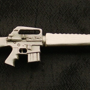 May include: A silver-colored metal replica of an assault rifle. The rifle has a black stock and a silver barrel. The rifle is a popular collectible for military enthusiasts.