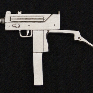 May include: A silver-colored metal replica of a machine gun. The gun has a long barrel and a stock that folds to the side.