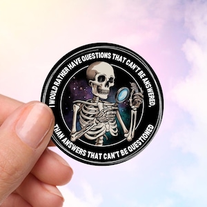 May include: A black and white sticker featuring a skeleton holding a magnifying glass. The sticker reads "I would rather have questions that can't be answered, than answers that can't be questioned."