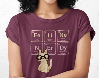 May include: A maroon t-shirt with a graphic of a cat wearing glasses and surrounded by periodic table elements. The elements are Fe, Li, Ne, N, Er, and Dy.