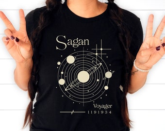 May include: Black t-shirt with a white graphic of a solar system with the text "Sagan Voyager 1191934".