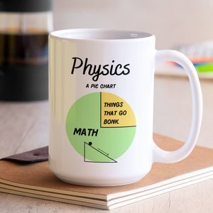May include: White ceramic mug with a green and yellow pie chart that says "Physics: A Pie Chart" and "Math" on one side and "Things that go bonk" on the other side.