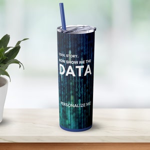 Könnte beinhalten: Ein Edelstahlbecher mit blauem Deckel und blauem Strohhalm. Der Becher hat ein schwarz-blaues Design mit einem Binärcode-Muster und dem Text "COOL STORY. NOW SHOW ME THE DATA PERSONALIZE ME!"
