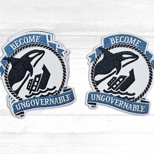 May include: Two blue and white embroidered patches with the text "Become Ungovernable" and a black silhouette of an orca whale jumping over a sinking ship.