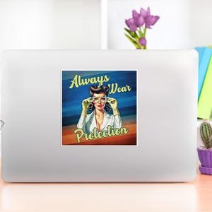 Pode incluir: Um adesivo em um laptop branco com uma ilustra&ccedil;&atilde;o retr&ocirc; de uma mulher usando &oacute;culos e luvas. O texto "Always Wear Protection" &eacute; exibido em uma fonte vintage. O fundo tem listras azuis e laranja.