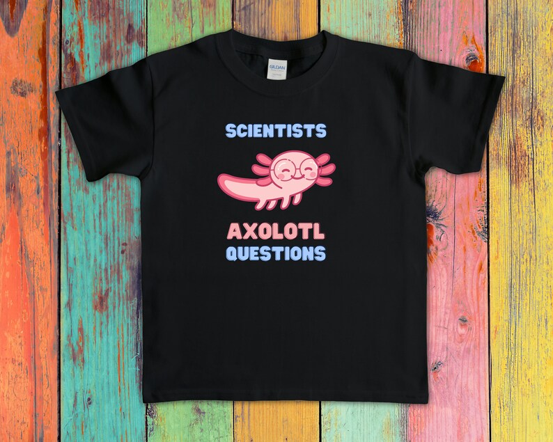 Puede incluir: Una camiseta negra de manga corta con un gr&aacute;fico de un ajolote rosa que lleva gafas redondas. El texto sobre el ajolote dice SCIENTISTS y el texto debajo dice AXOLOTL QUESTIONS en letras de color azul claro y rosa en la parte frontal.