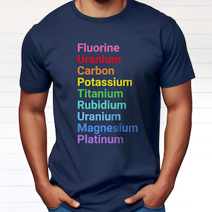 May include: A navy blue short-sleeved t-shirt featuring a vertical list of chemical elements printed in rainbow colors: Fluorine, Uranium, Carbon, Potassium, Titanium, Rubidium, Uranium, Magnesium, and Platinum, arranged to spell out a specific word.