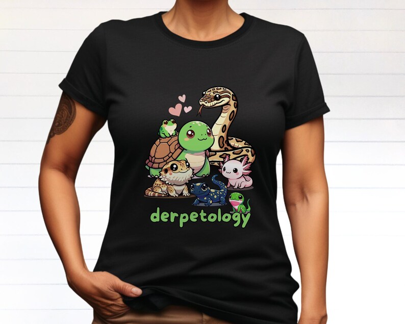 K&ouml;nnte beinhalten: Ein schwarzes Kurzarm-T-Shirt mit einer grafischen Illustration einer Schlange, einer Schildkr&ouml;te, eines Frosches, eines Axolotls, einer Eidechse und eines Salamanders mit drei kleinen rosa Herzen. Darunter steht der Text derpetology in gr&uuml;nen Buchstaben.