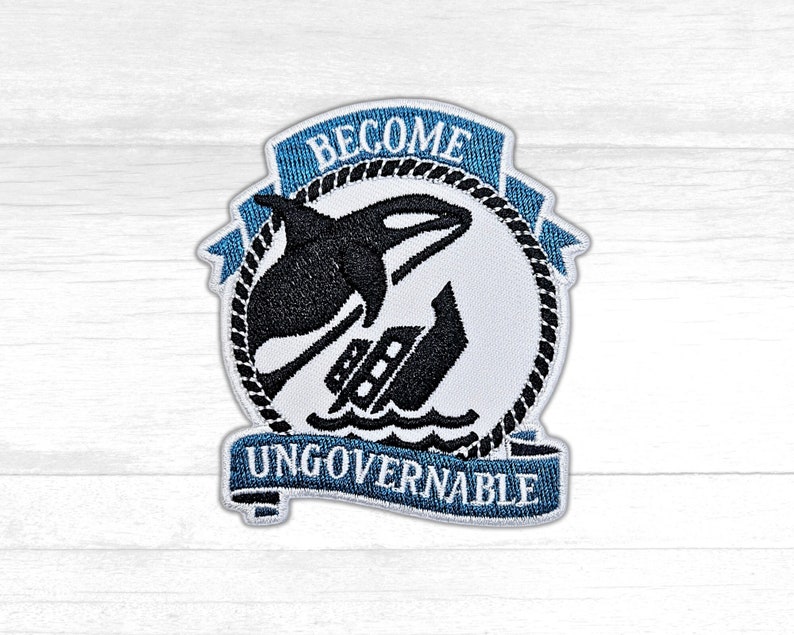 May include: A white and blue embroidered patch with a black orca jumping over a ship. The patch has the text "Become Ungovernable" on a blue banner.