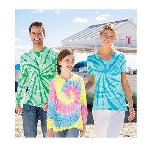 May include: A family of three wearing tie-dye shirts. The father is wearing a green and white tie-dye long-sleeve shirt, the mother is wearing a blue and white tie-dye short-sleeve shirt, and the child is wearing a yellow, pink, and blue tie-dye long-sleeve shirt.