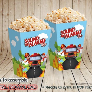 Puede incluir: Dos cajas de palomitas de maíz llenas de palomitas de maíz. Las cajas son de color azul claro con un diseño de camión de bomberos y bombero de dibujos animados. El texto en las cajas dice "SOUND THE ALARM!". Las cajas están etiquetadas como "Easy to assemble" y "DIGITAL DOWNLOAD".