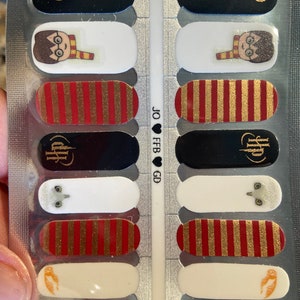 May include: A sheet of nail polish wraps with a Harry Potter theme. The wraps feature images of Harry Potter, an owl, and the Hogwarts crest. The wraps also feature red and gold stripes.