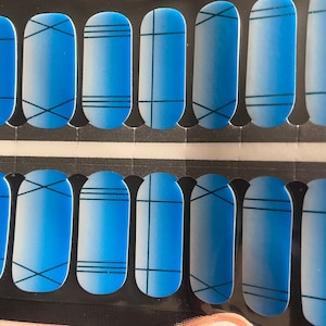 May include: A sheet of blue and white nail polish wraps with a geometric design. The wraps are arranged in a grid pattern on a black background.