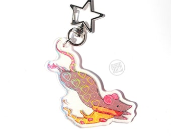 May include: A clear acrylic keychain featuring a cartoon mouse holding a slice of pizza. The keychain has a holographic effect with a pattern of hearts. The keychain is attached to a silver star-shaped clip.