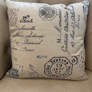 Peut inclure: Un coussin beige avec un motif parisien vintage comportant du texte noir et des timbres. Le texte comprend "Mademoiselle", "Rue Diserand", "Paris France" et "M. Monsieur Gustave Antoine".