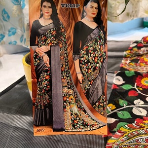 May include: A black and gray saree with a floral print. The saree has a silver border and a black blouse. The image also includes the text "TULIP" and "4522".