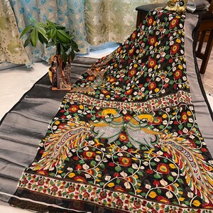 May include: Black saree with a colorful floral and peacock design. The saree has a silver border and a white background with black floral accents.