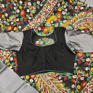 May include: A black blouse with a green trim and a floral pattern on the back. The blouse has a scoop neck and short sleeves.