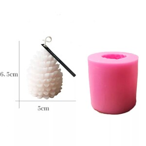 May include: Pink silicone mold for making a pine cone shaped candle. The mold is 5 inches in diameter and 6.5 inches tall. A white pine cone candle is shown next to the mold.