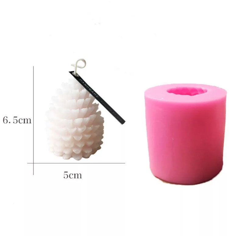 May include: Pink silicone mold for making a pine cone shaped candle. The mold is 5 inches in diameter and 6.5 inches tall. A white pine cone candle is shown next to the mold.