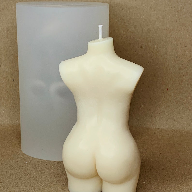 May include: A white candle shaped like a human torso. The candle is sitting on a clear silicone mould.