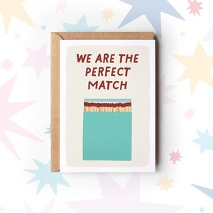 May include: A greeting card with a teal blue box of matches and the text "We are the perfect match".