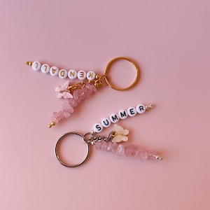 May include: Two pink and gold keychains with pink crystal beads and white butterfly charms. One keychain spells "KENDAL" and the other spells "SUMMER".