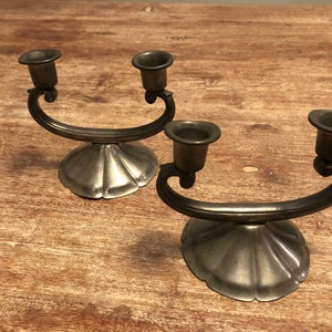 May include: Two silver candle holders with a decorative design. Each holder has two candle cups.