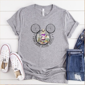May include: A gray t-shirt with a Mickey Mouse silhouette featuring a spiderweb design and the text "Nightmare Before Coffee". The design includes a ghost, a pumpkin, and coffee cups.