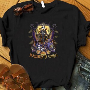 May include: Black t-shirt with a graphic of Jack Skellington from The Nightmare Before Christmas. The graphic features Jack Skellington standing in front of a spooky Halloween scene with pumpkins, bats, and other characters. The text "Halloween is Coming" is printed below the graphic.