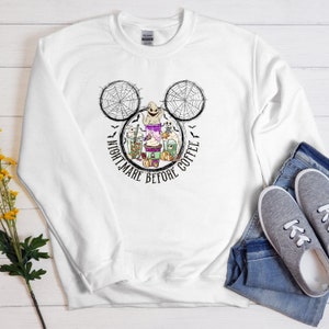 May include: White sweatshirt with a black and white Mickey Mouse head design featuring a ghost, spiderwebs, and coffee cups. The text "Nightmare Before Coffee" is written around the Mickey Mouse head.