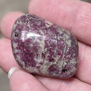 May include: A smooth, polished, pink and white tumbled stone with black flecks.