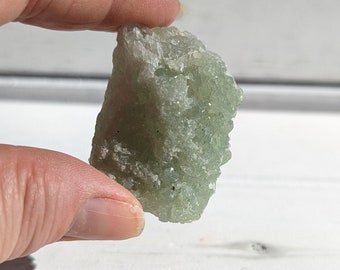 May include: A small, rough, green and white crystal with a natural, irregular shape.