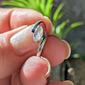 May include: A silver ring featuring a clear, faceted gemstone set in a leaf-shaped design.