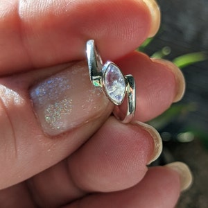 May include: A silver ring featuring a marquise-shaped moonstone. The ring is worn on a finger.
