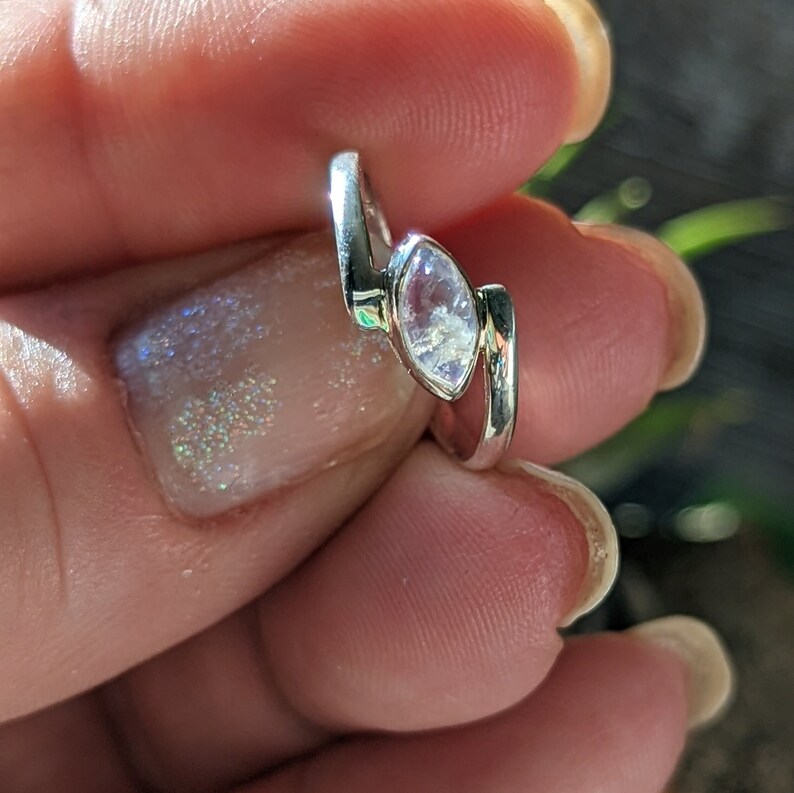May include: A silver ring featuring a marquise-shaped moonstone. The ring is worn on a finger.